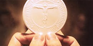 priest hands holding host at consecration
