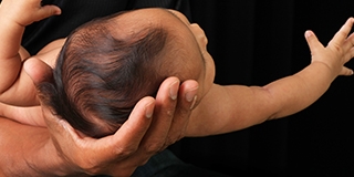 Newborn baby in her father's hand.