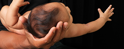 Newborn baby in her father's hand.
