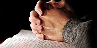 praying hands on a bible