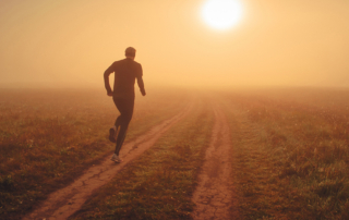 man running into sunrise on deserted road
