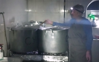 Ukraine soup kitchen workers stir soup with light from a head lamp